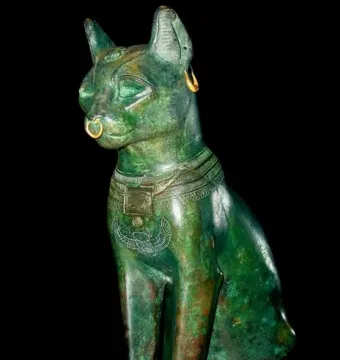 Gayer-Anderson Cat statue with a gold nose ring, earring, and decorated collar.