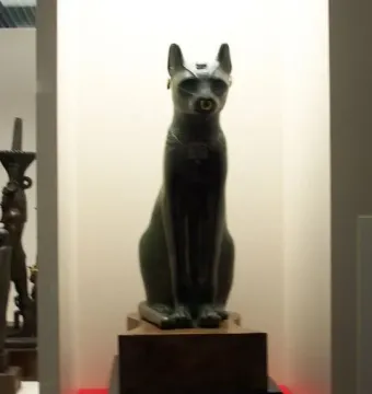 The Gayer-Anderson cat statue with pointed ears, a nose ring, and gold-colored ear cuffs on a tiered base.
