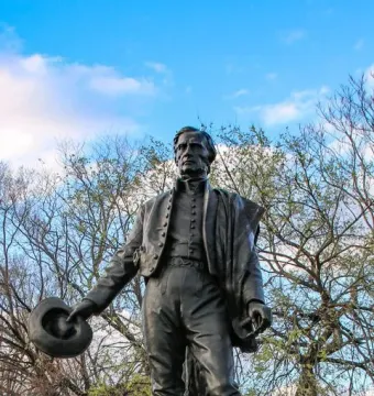 Bronze statue of General José Gervasio Artigas standing outdoors with a hat in his left hand.
