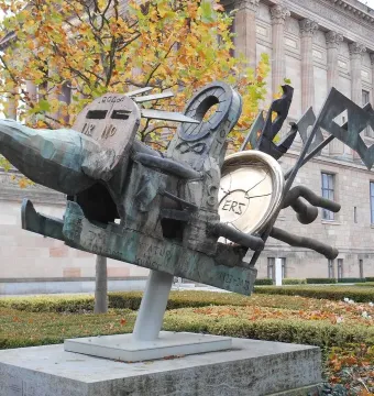 Humpty Dumpty sculpture with bronze mechanical forms, a golden disc marked \