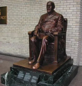 Timothy Eaton bronze statue seated in a chair on a marble pedestal with plaques.