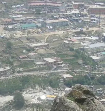Aerial view of a town spread across a valley beside a winding river, framed by rocky foreground outcrops.