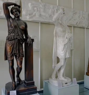 Classical Amazon statues displayed in a museum gallery, with three draped female figures standing before relief panels.