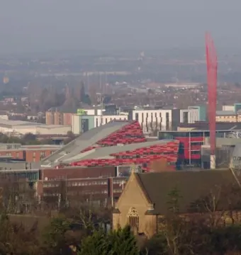 Aspire, a tall red sculpture of interwoven beams rising above the campus buildings and trees.