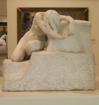 Desolation, a white marble sculpture of a nude kneeling figure with bowed head and long hair draped over the face.