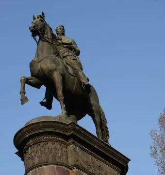 Monument to Mykola Shchors, a bronze equestrian statue on an ornate pedestal against a blue sky.