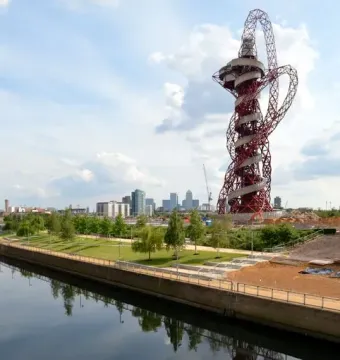 Orbit Tower rising beside a canal, with its twisting steel structure reflected in the water.