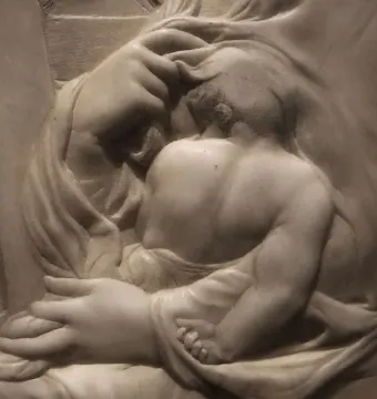 Madonna of the Stair marble relief showing a child nestled against an adult figure with hands supporting the child.