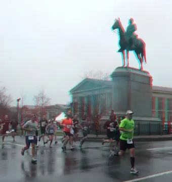 Robert E. Lee Monument with runners on a wet street in front of an equestrian statue on a tall stone base.