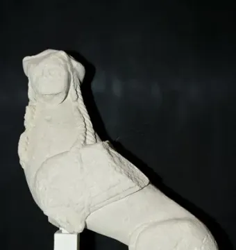 Stone Sphinx of Agost sculpture with a human-like head and animal body on a white plinth.