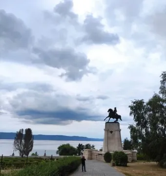 Tatishchev Monument on a tiered stone pedestal beside a waterfront walkway.