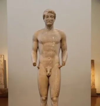 Aristodikos Kouros, a nude marble statue of a male figure with curly hair and missing forearms.