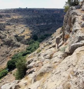 Rocky canyon landscape near the Karasu relief with steep cliffs and a green valley floor.