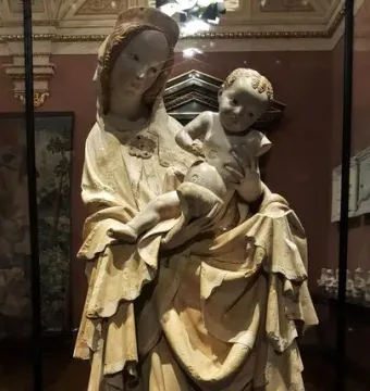 Krumlov Madonna sculpture of a woman holding a child behind glass in a museum