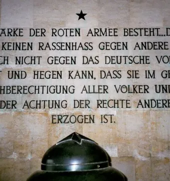 German inscription on a tiled wall at the Soviet War Memorial Schönholzer Heide, with a black star above it and the top of a dark dome at the bottom.