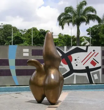 Cloud Shepherd, a bronze abstract sculpture with rounded forms and a central peak, stands in front of a geometric tiled wall.