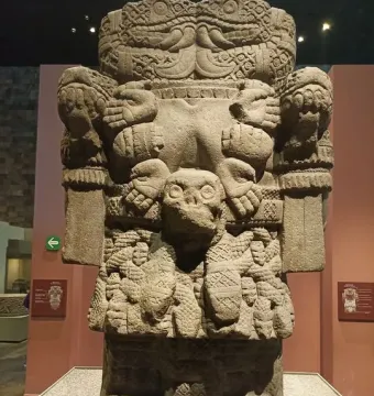 Coatlicue stone statue with a skull-like head, clawed feet, and carved symbolic patterns