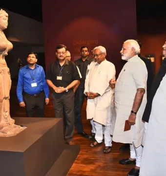 Didarganj Yakshi stone sculpture on a pedestal, with a crowned female figure holding an object and a broken left hand.