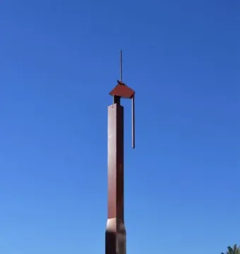 The Pink Panther sculpture rises from a shallow reflecting pool beneath a clear blue sky.
