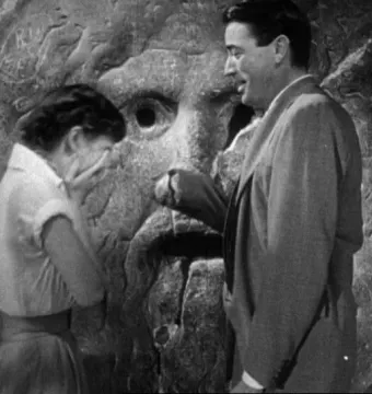Bocca della Verità stone mask with a man placing his hand in the mouth beside a woman covering her face