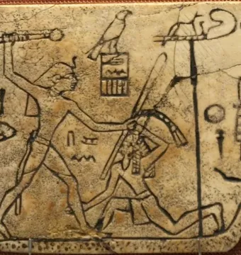 Ancient ivory plaque with incised figures showing a standing ruler raising a mace over a kneeling figure, with symbols and a sandal shape beside them.