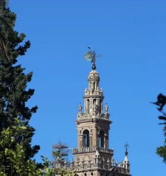 The Giraldillo statue atop a tall tower, with a circular shield against a clear blue sky.