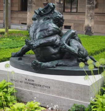 Bronze sculpture of Hercules wrestling the Nemean Lion on a stone pedestal.