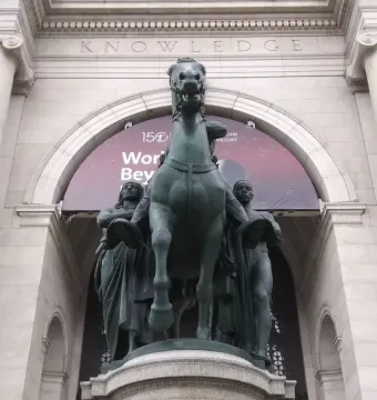 Theodore Roosevelt Equestrian Statue with a rearing horse and two standing figures in front of the American Museum of Natural History.