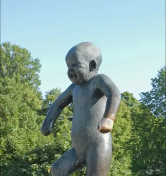 Angry Boy bronze statue of a crying toddler with clenched fists on a pedestal.