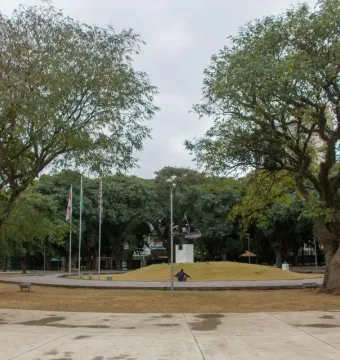Ayrton Senna Monument on a raised grassy mound in a park, with a paved circular path and trees around it.