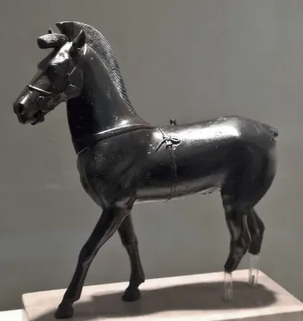 Bronze horse statuette from Olympia shown in profile on a pedestal.