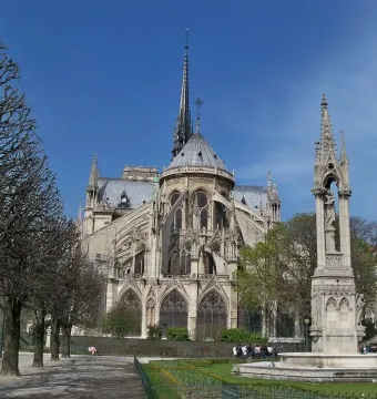 Fontaine de la Vierge monument in front of Notre-Dame Cathedral with its spire and flying buttresses.