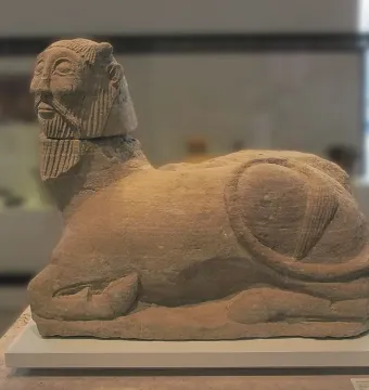 The Bicha of Balazote stone sculpture, showing a recumbent mythical creature with a human head, beard, and animal body.