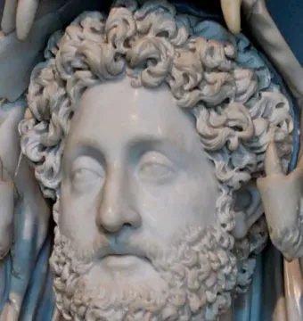 Marble bust of Commodus as Hercules with curly hair and beard, showing part of the lion skin draped around the shoulders.
