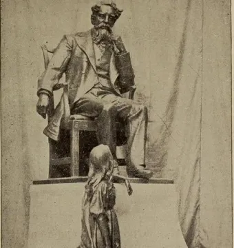 Dickens and Little Nell sculpture showing a seated bearded man and a standing girl looking up at him.