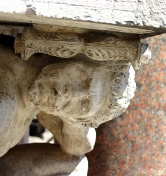 Close-up of Il Gobbo di Rialto, showing a weathered stone crouching figure supporting a carved element.