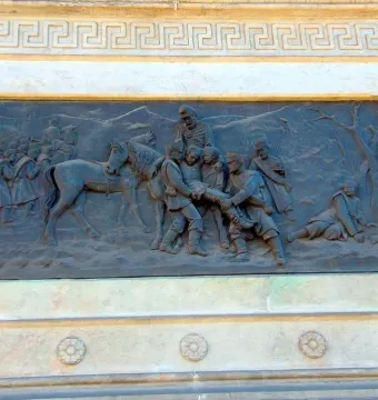 Bronze relief panel on the Marqués del Duero monument showing a battle scene with soldiers, a horse, and wounded figures.