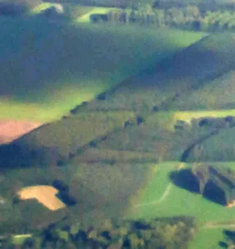 Aerial view of The Green Cathedral surrounded by green fields and a waterway.