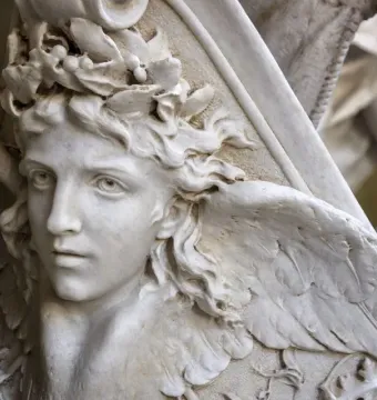 Close-up of Angelo Nocchiero, a white marble youthful figure with curly hair, a leafy crown, and a carved wing.