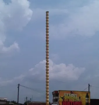 Colonne Pascale, a tall segmented column standing outdoors among buildings and vehicles.
