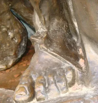 Close-up of Eustache de Saint Pierre’s bronze foot on a textured base, with bare toes beneath heavy drapery.