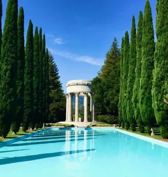 Pulgas Water Temple beside a long reflecting pool lined with tall evergreen trees.