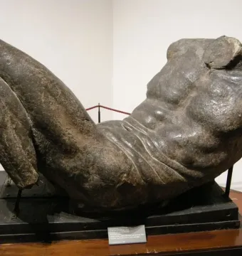 River God sculpture showing a dark reclining male torso with the head, arms, and lower legs missing.