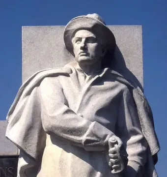 Soldiers\' Monument stone statue of a man in a wide-brimmed hat and long coat holding a sword or rifle hilt.