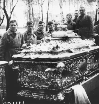 Alexander Nevsky reliquary casket on a flatbed vehicle with uniformed men standing nearby.