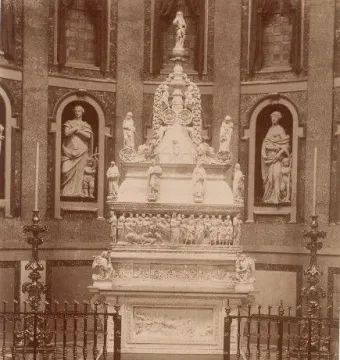 Arca di San Domenico inside a vaulted chapel, with a towering carved funerary monument, railings, and candelabras