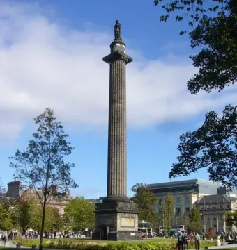 The Melville Monument rising above a green park with people walking along paved paths.
