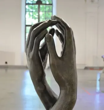 The Cathedral bronze sculpture with two hands reaching upward and nearly touching