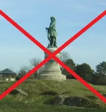 Vercingetorix Monument standing on a stone pedestal on a grassy hill with trees and a small gazebo in the background