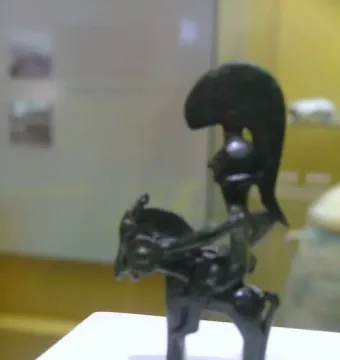 Warrior of Moixent horse-and-rider figurine with a crested helmet and round shield on a museum display stand.
